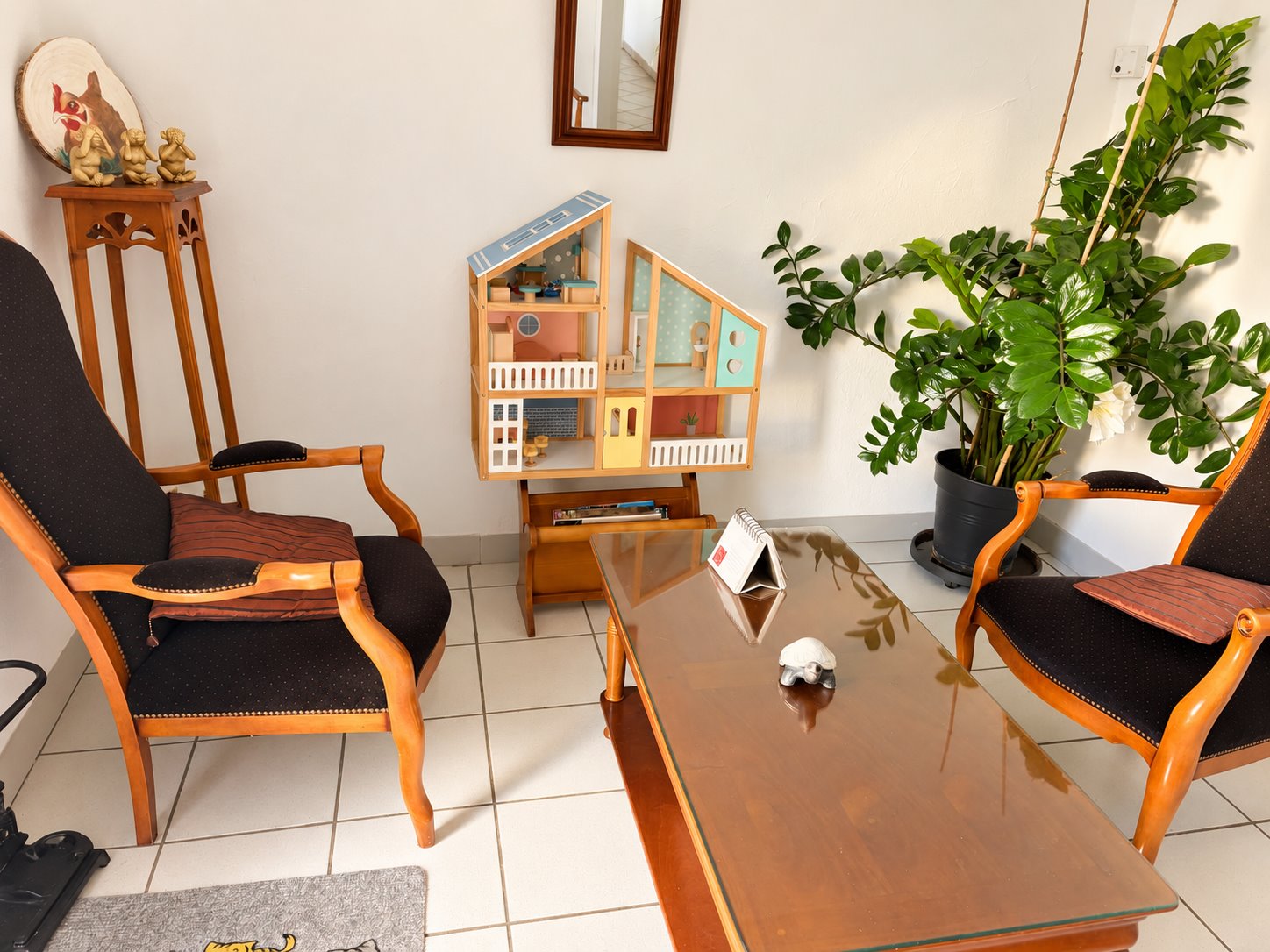 Pièce du cabinet avec fauteuils, table et maison de poupée.